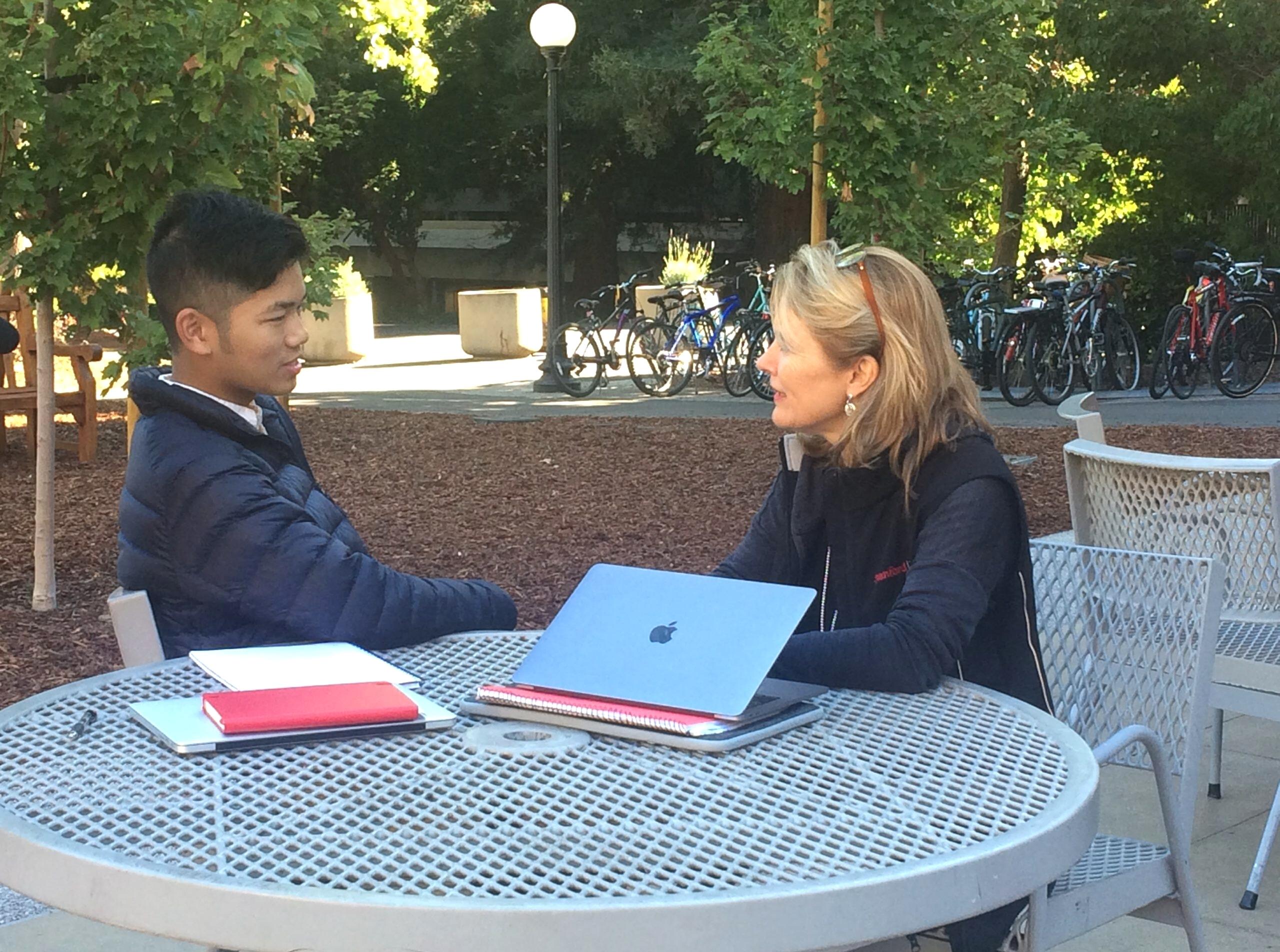 DCI Fellow speaking with a student at outdoor table