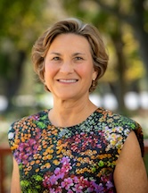 Headshot of Katie Connor wearing print blouse with black background.