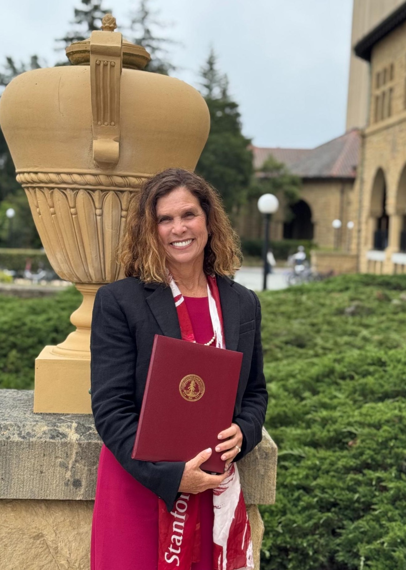 DCI Fellow Jane McConnell wearing a red dress and black blazer standing in front of Stanford Quad.