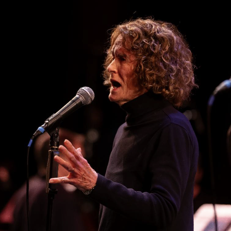 Profile of DCI Fellow Joan Jeffri (2023) singing in front of a microphone.