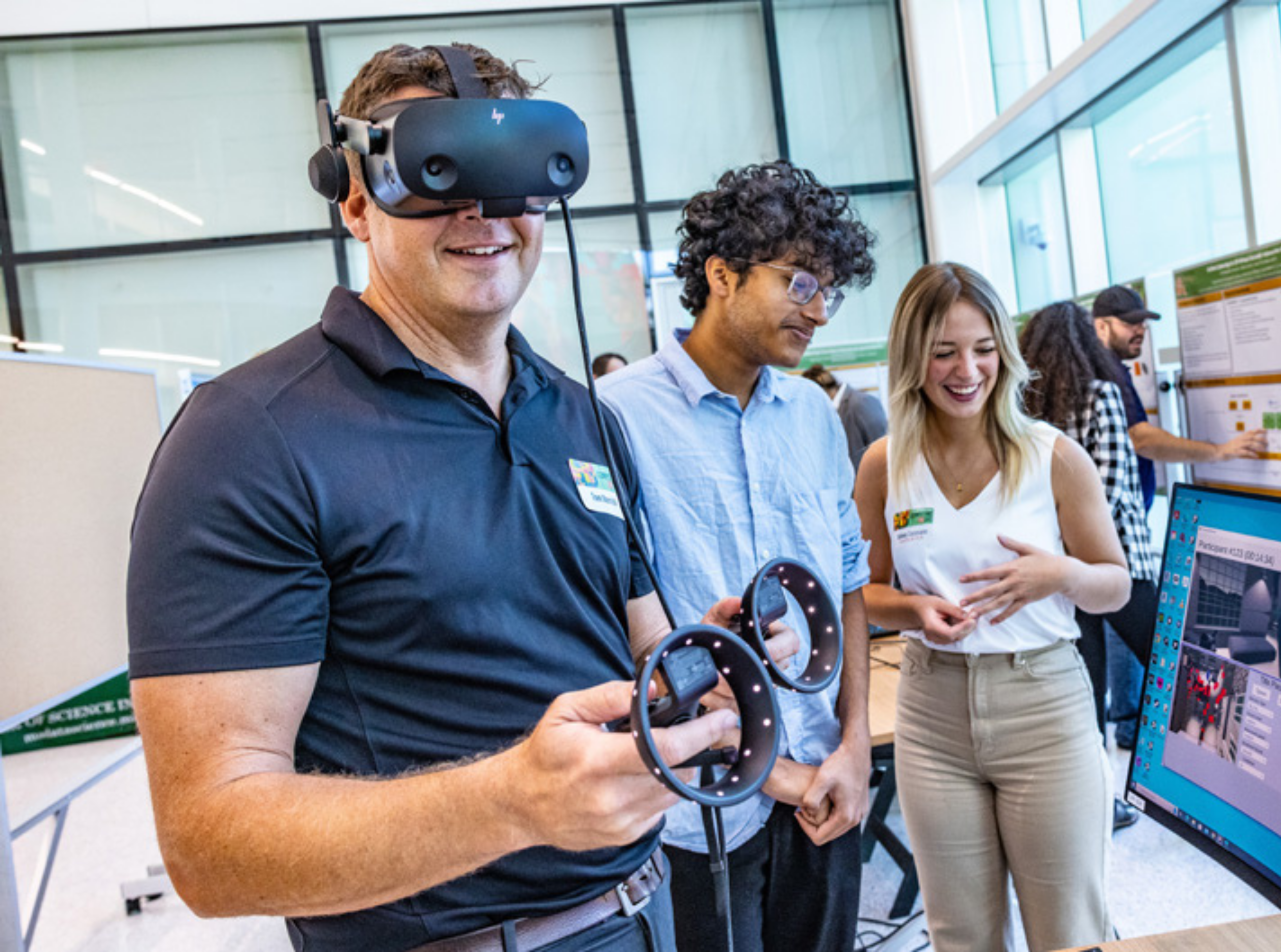 Tom Merrick (DCI 2020) holding VR equipment, standing next to students.